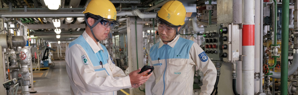 Image of two frontline workers in a factory holding a mobile phone.